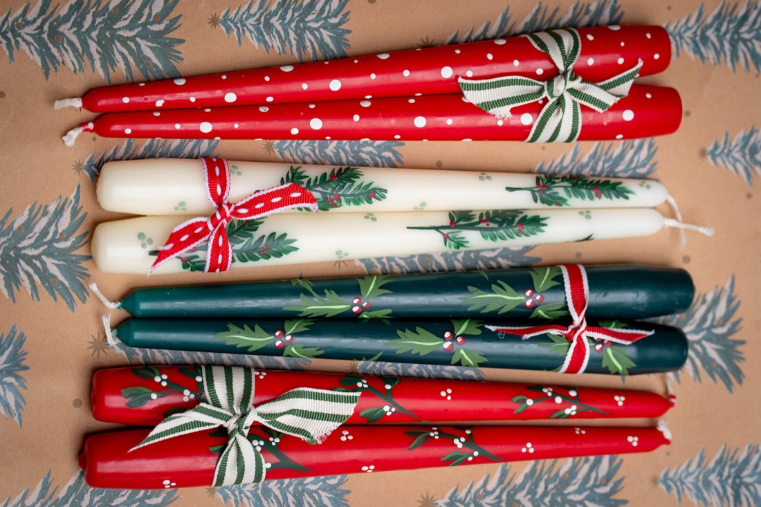 Red Christmas candles painted by hand with festive botanical details.