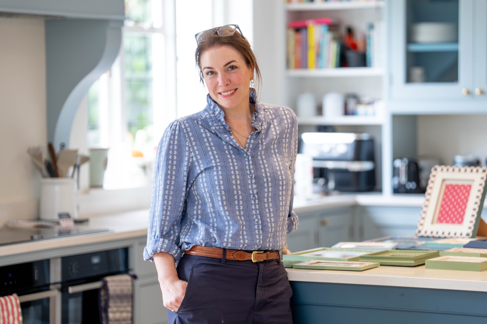 Ellie standing beside her kitchen worktop with hand painted frames.