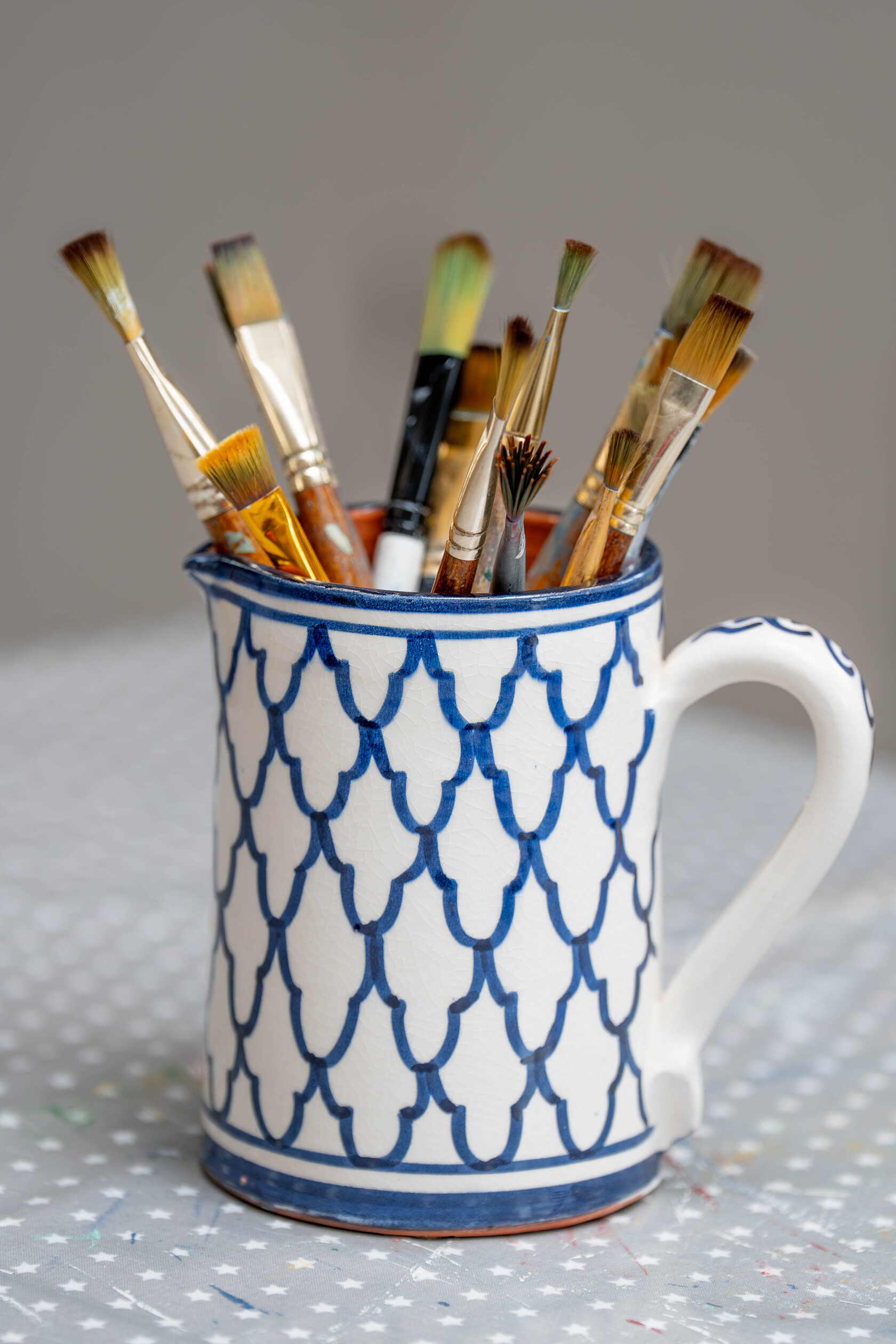 Ellie’s paintbrushes in a blue and white patterned jug.