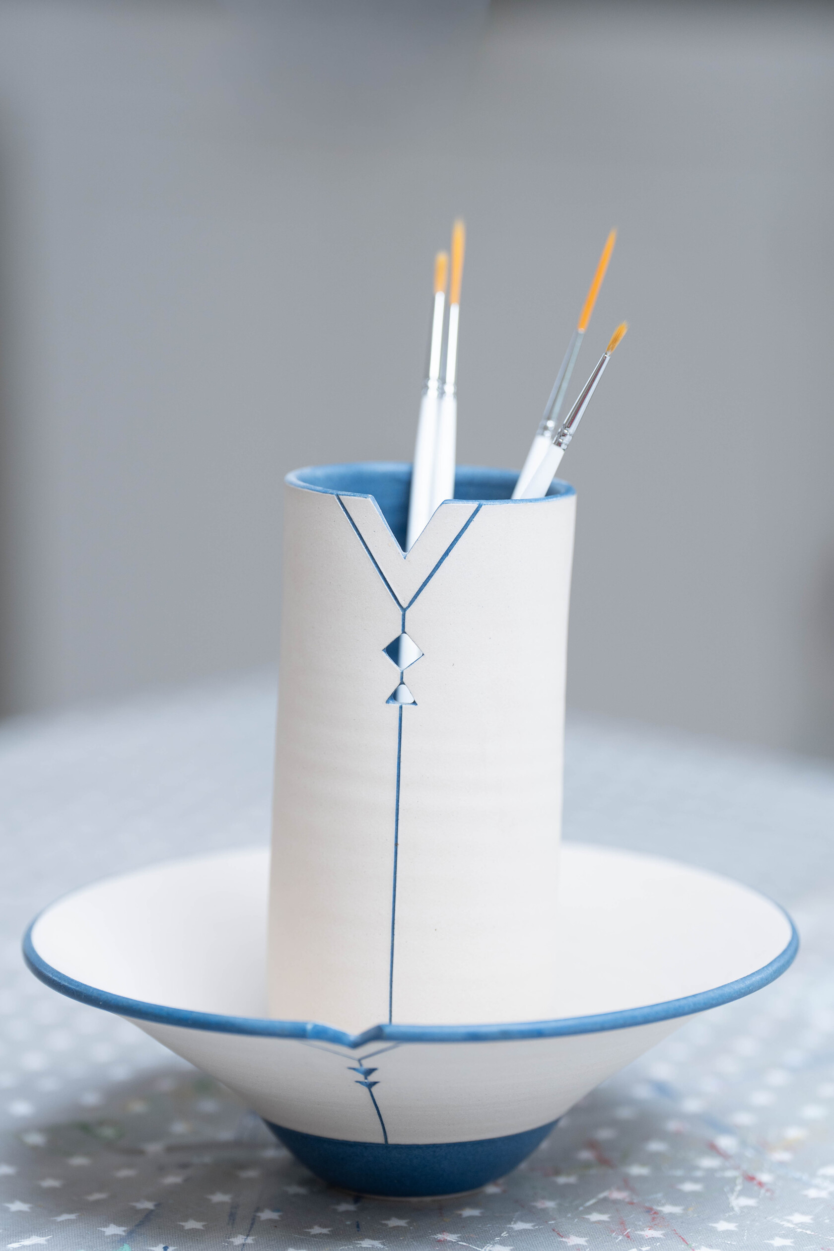 Fine paintbrushes in a blue and white ceramic brush holder.