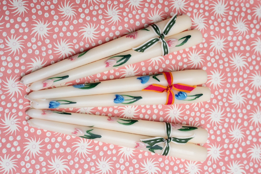 Hand painted floral candles, tied in pairs with colourful ribbons.